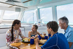Family enjoys lunch aboard reef cruise during Whitsundays Reef Tour. Relaxing meal with ocean views on Brisbane to Cairns trip.