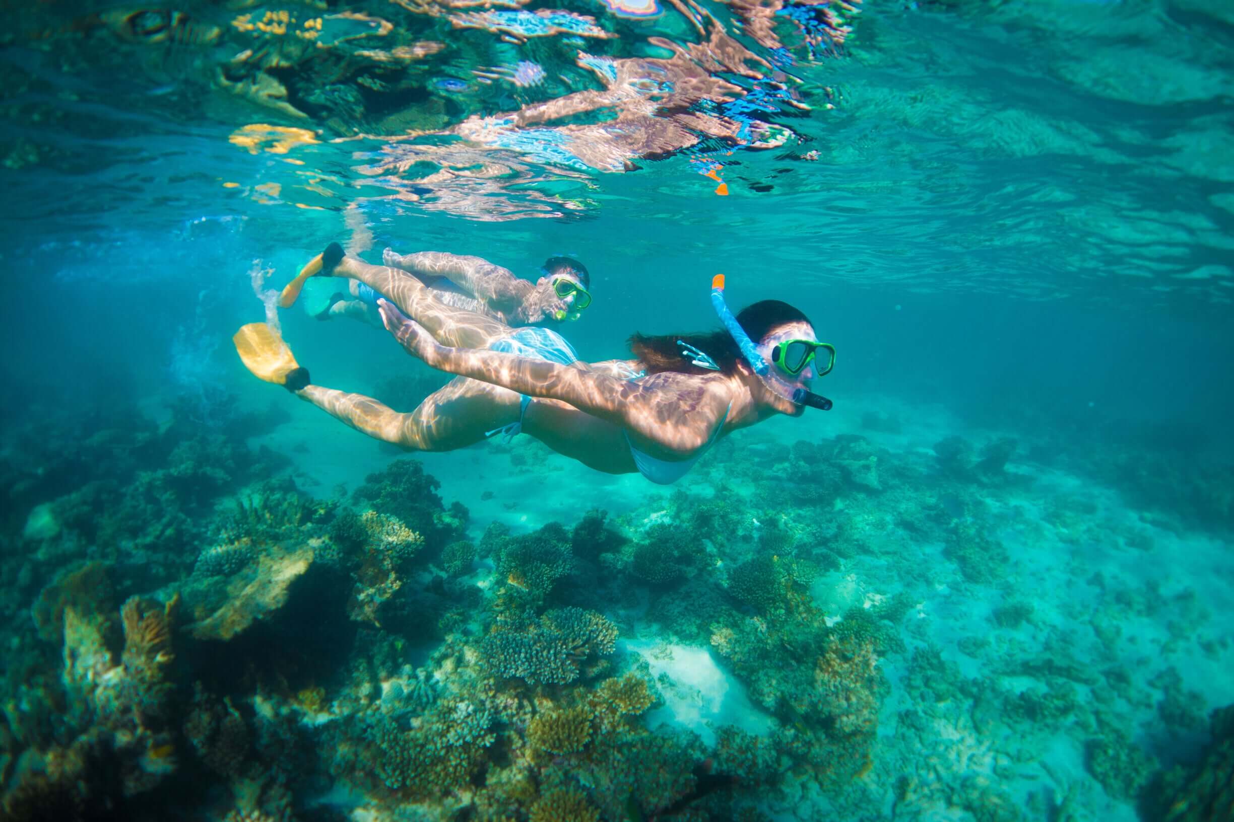 Couple snorkeling over coral reef at Ningaloo during West Coast Road Trip. Underwater adventure in Western Australia.