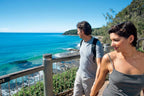 Couple hiking Noosa coastal trail with ocean views on East Coast Australia tour. Scenic walk on 8-day Sydney to Brisbane itinerary.