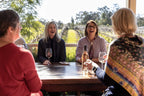 Group enjoying wine at vineyard on East Coast Australia tour. Winery experience on 8-day Sydney to Brisbane itinerary.