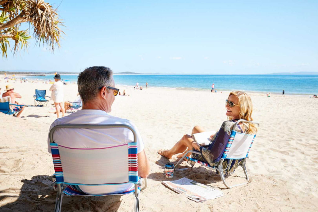 Couple relaxing on Noosa beach during East Coast Australia tour. Leisure stop on 8-day itinerary from Sydney to Brisbane.