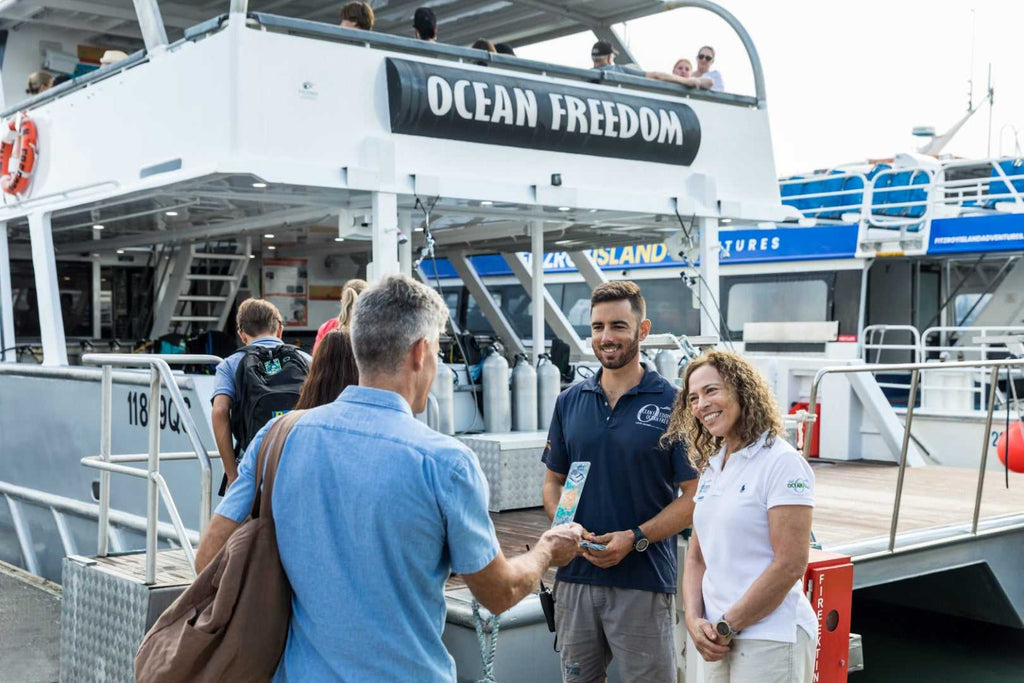 Travelers boarding Ocean Freedom boat for reef tour on East Coast Adventure 14/16-Day Small-Group Tour. Start of Great Barrier Reef excursion.