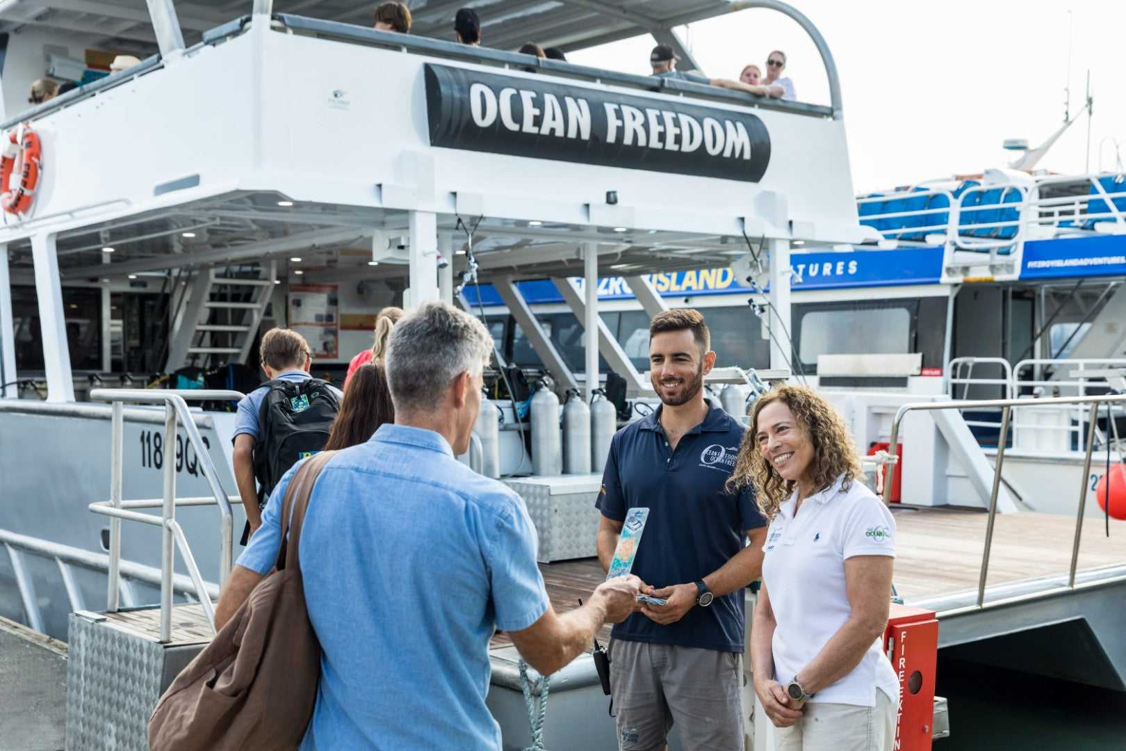Travelers boarding Ocean Freedom boat for reef tour on East Coast Adventure 14/16-Day Small-Group Tour. Start of Great Barrier Reef excursion.