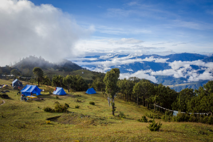 Blue camping tents set up on a mountain ridge along the Trans Bhutan Trail, offering scenic overnight stays.