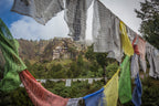Colorful prayer flags framing a view of Tiger’s Nest Monastery, a sacred site on the Trans Bhutan Trail.
