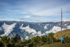 Hiker gazing at panoramic mountain views and clouds, enjoying the scenic Trans Bhutan Trail trek.