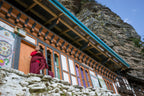 Monk standing outside a cliffside monastery, a spiritual stop on the Trans Bhutan Trail journey.