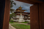 Framed view of a stupa and temple through wooden gates, a peaceful scene on the Trans Bhutan Trail.