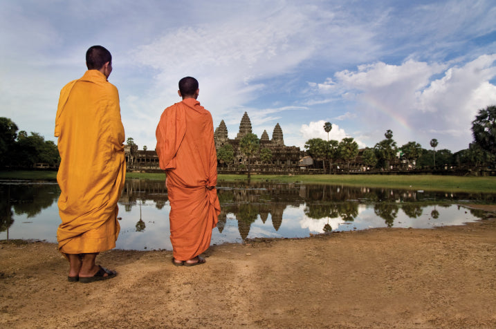 Two monks in orange robes admire Angkor Wat at sunrise, part of the Angkor to Islands 16-Day Tour - Khmer Culture to Thai Coasts experience.