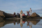 Group of people standing on rocks with their reflections in the water below.