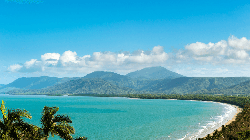 Palm-fringed coastline and turquoise waters in Port Douglas on East Coast Adventure 14/16-Day Small-Group Tour. Tropical beach paradise.