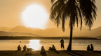 People watching sunset by the beach in Port Douglas on East Coast Adventure 14/16-Day Small-Group Tour. Relaxing tropical evening.