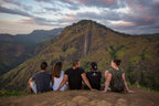 Travelers sitting on hilltop overlooking Ella Rock at sunset. Explore Sri Lanka - Land & Sea Tour Options features breathtaking mountain views.