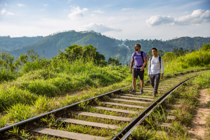 Two men walking along scenic railway tracks in Sri Lanka’s hill country. Explore Sri Lanka - Land & Sea Tour Options includes off-the-beaten-path hikes.