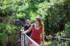 Woman crossing rope bridge in lush forest during Sri Lanka tour. Explore Sri Lanka - Land & Sea Tour Options offers active outdoor experiences.