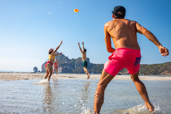 Travelers play frisbee on a Thai beach, enjoying the coastal fun of the Angkor to Islands 16-Day Tour - Khmer Culture to Thai Coasts.