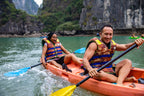 Tourists kayaking in emerald waters surrounded by limestone cliffs in Vietnam. Featured in Vietnam Hiking and Cycling Tour adventure package.