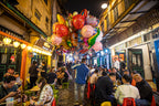 Night market in Vietnam bustling with diners and balloon vendor. Evening cultural experience on Vietnam Hiking and Cycling Tour.
