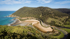 Breathtaking view of Victoria's coastline, featuring lush hills and a serene beach on the Great Ocean Walk.