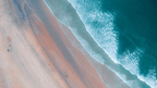 Aerial view of a serene beach meeting the ocean, showcasing coastal beauty for outdoor adventures.