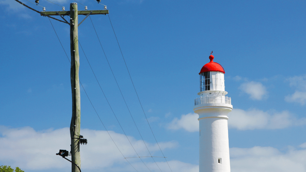 Iconic lighthouse with red dome against clear blue sky, symbolizing coastal adventure and scenic travels.