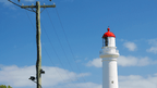 Iconic lighthouse with red dome against clear blue sky, symbolizing coastal adventure and scenic travels.