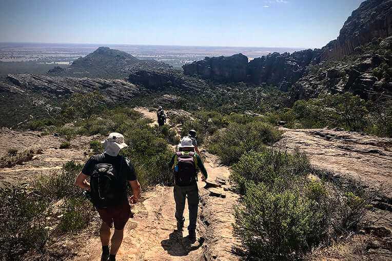 Group hiking on a rugged trail in the Grampians, enjoying breathtaking views and an adventurous outdoor experience.
