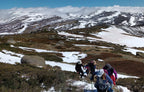 Hikers on a mountain trail with snow and rocky terrain