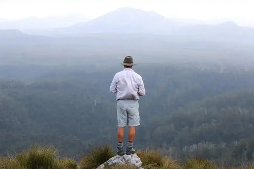 Man standing on a rocky outcrop overlooking a misty mountain landscape