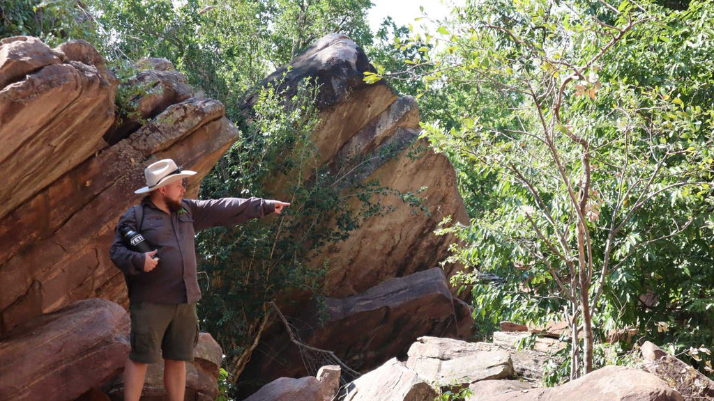 Tour guide pointing out features in rocky forest at Kakadu Litchfield Camping Adventure - 3-Day Tour. Educational nature walk experience.