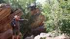 Tour guide pointing out features in rocky forest at Kakadu Litchfield Camping Adventure - 3-Day Tour. Educational nature walk experience.