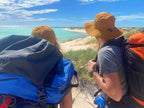 Hikers with backpacks gaze at the turquoise Ningaloo Coast during an adventurous trek in Western Australia.