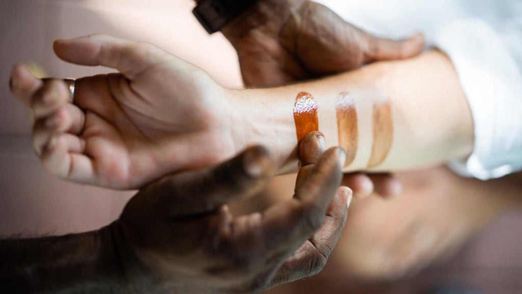 Aboriginal guide applies ochre paint to tourist's arm on Kakadu Katherine Gorge Tour | 4-Day Comfort Travel. Cultural body art demonstration.