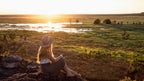 Woman watches sunset over wetlands from rocky ledge on Kakadu Katherine Gorge Tour | 4-Day Comfort Travel. Peaceful end to adventure day.