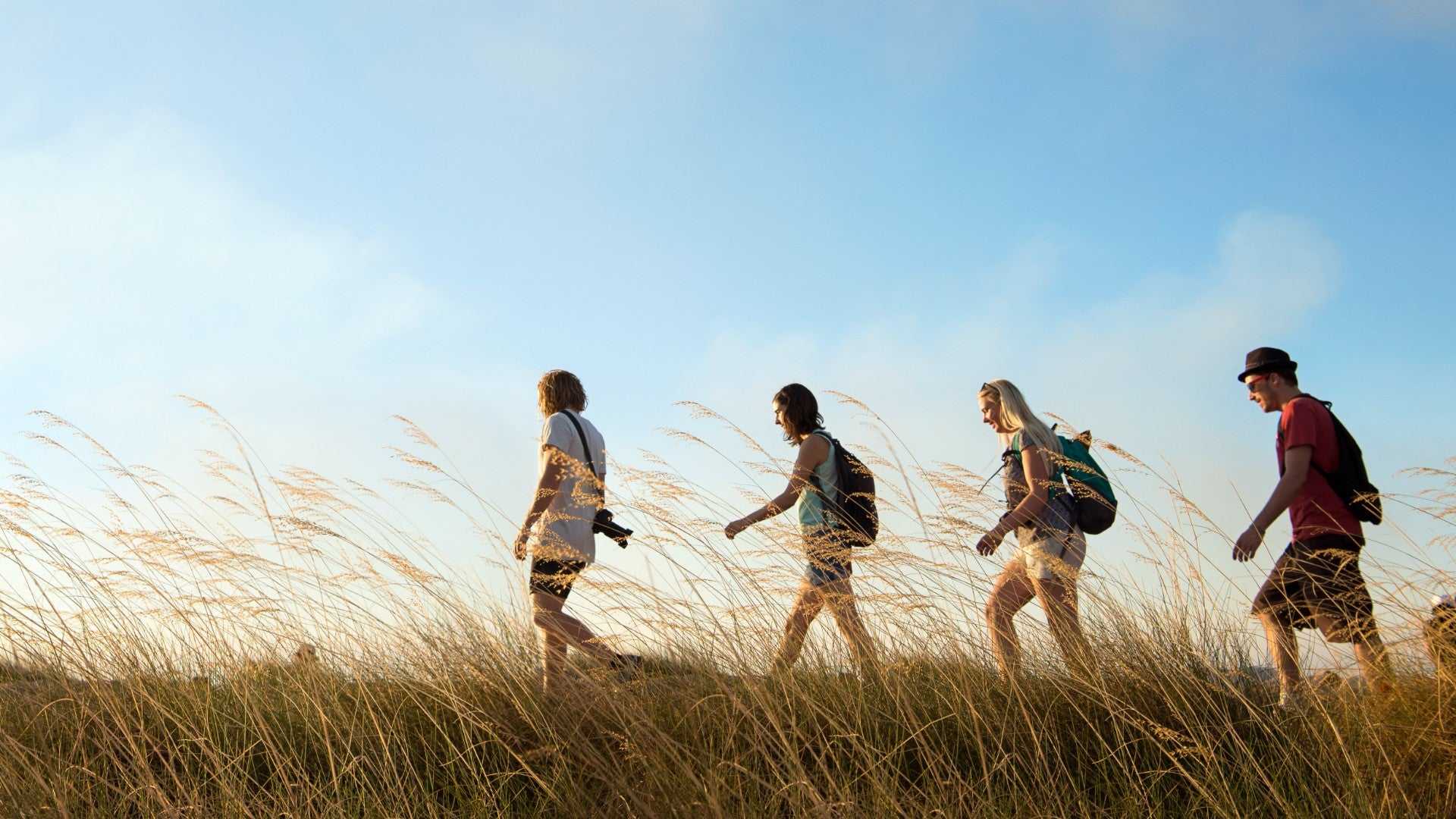 Group hiking through tall grass at Kakadu Litchfield Camping Adventure - 3-Day Tour. Outdoor adventure in open savannah landscape.