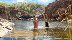 Couple plays in natural swimming hole on Kakadu Katherine Gorge Tour | 4-Day Comfort Travel. Refreshing dip in scenic outback location.