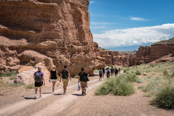 Tour group exploring Charyn Canyon’s rugged trails in Kazakhstan, part of the multi-activity adventure on the 14-23 Day Central Asia Silk Road Tour.