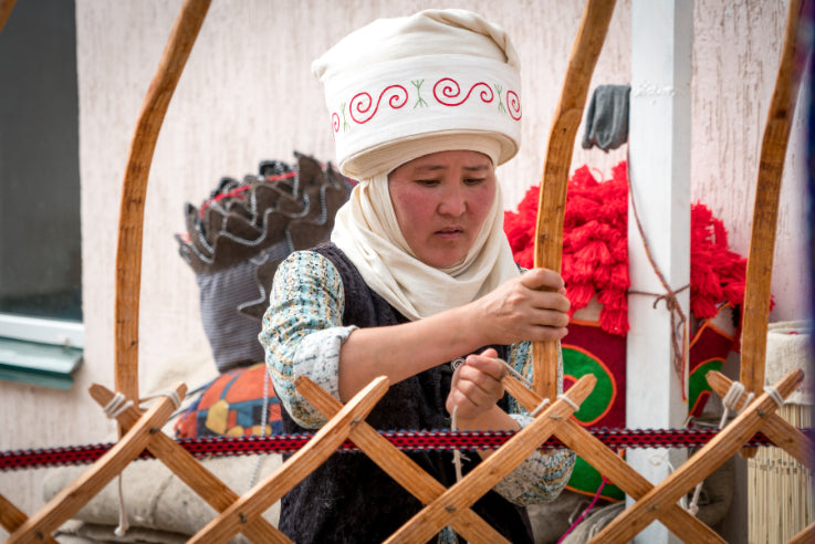 Kyrgyz woman weaving traditional yurt frame, a cultural immersion activity on the 14-23 Day Central Asia Silk Road Tour.