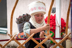 Kyrgyz woman weaving traditional yurt frame, a cultural immersion activity on the 14-23 Day Central Asia Silk Road Tour.