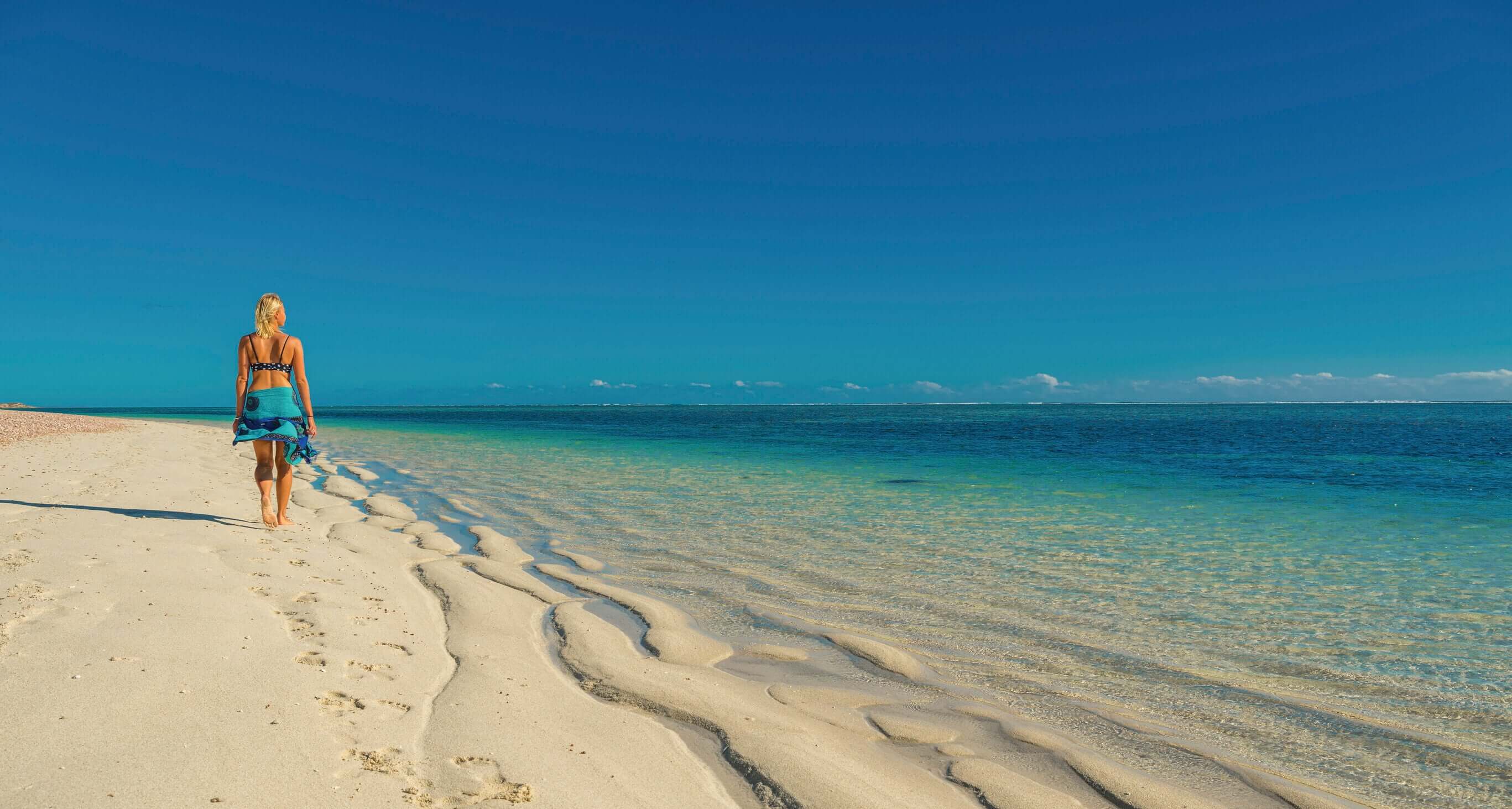 Traveler walking along pristine beach at Exmouth during West Coast Road Trip. Coastal exploration in Western Australia.
