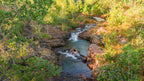Small cascading stream in lush forest at Kakadu Litchfield Camping Adventure - 3-Day Tour. Gentle waterfalls and rocky pools in natural setting.