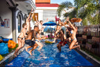 Group jumps into pool at a lively hostel, celebrating fun moments on the Angkor to Islands 16-Day Tour - Khmer Culture to Thai Coasts.