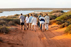 Group hiking along red dirt trail near Shark Bay on West Coast Road Trip from Perth to Exmouth. Outdoor adventure in Western Australia.