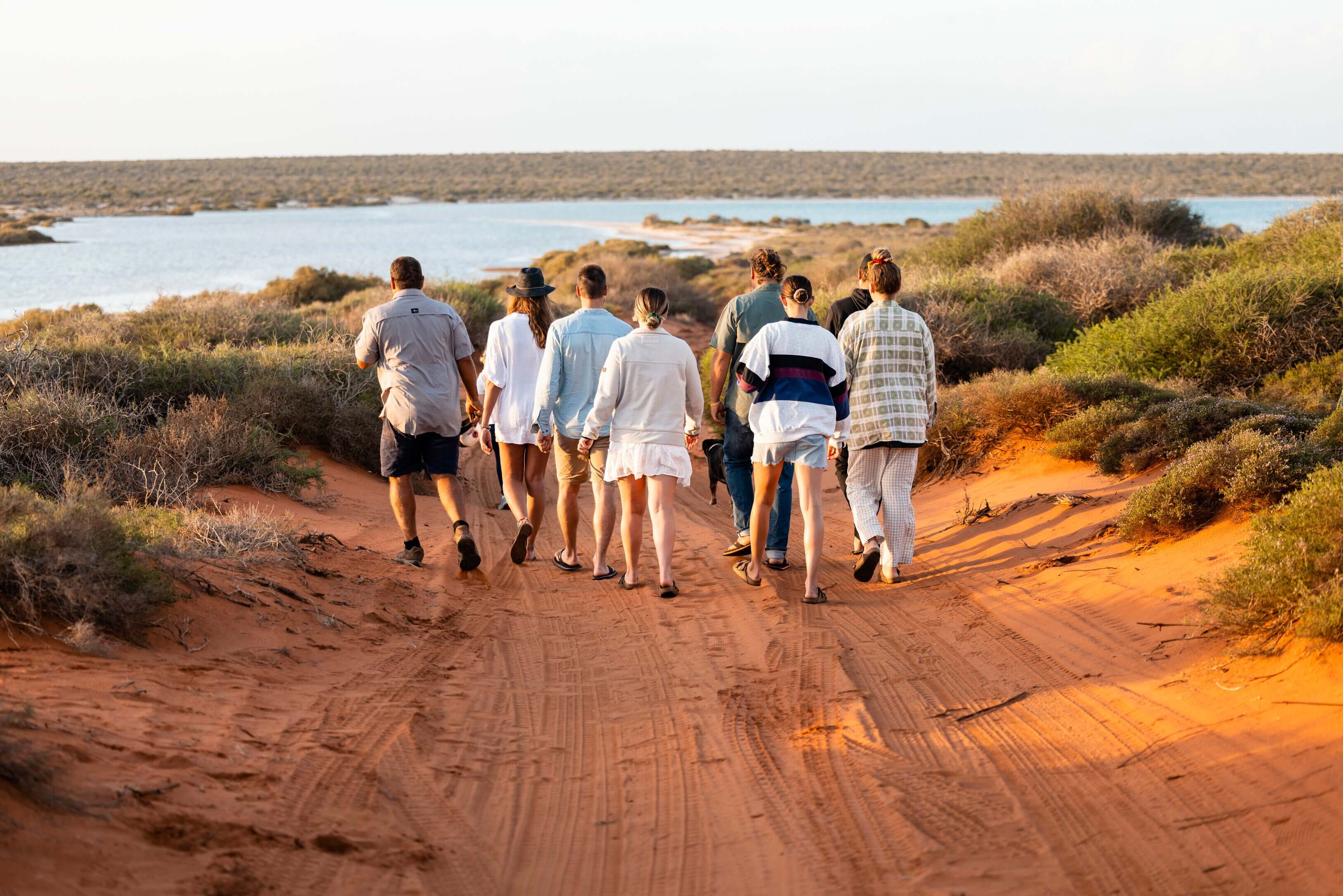Group hiking along red dirt trail near Shark Bay on West Coast Road Trip from Perth to Exmouth. Outdoor adventure in Western Australia.