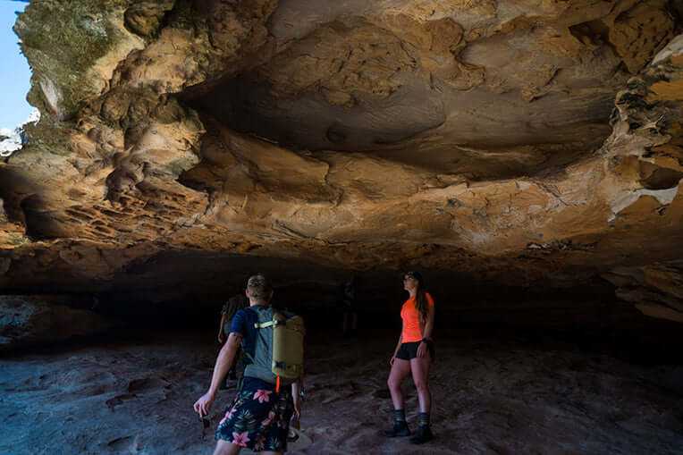 Adventure seekers exploring a stunning rock cave on the Grampians Peaks Trail, embracing the great outdoors.