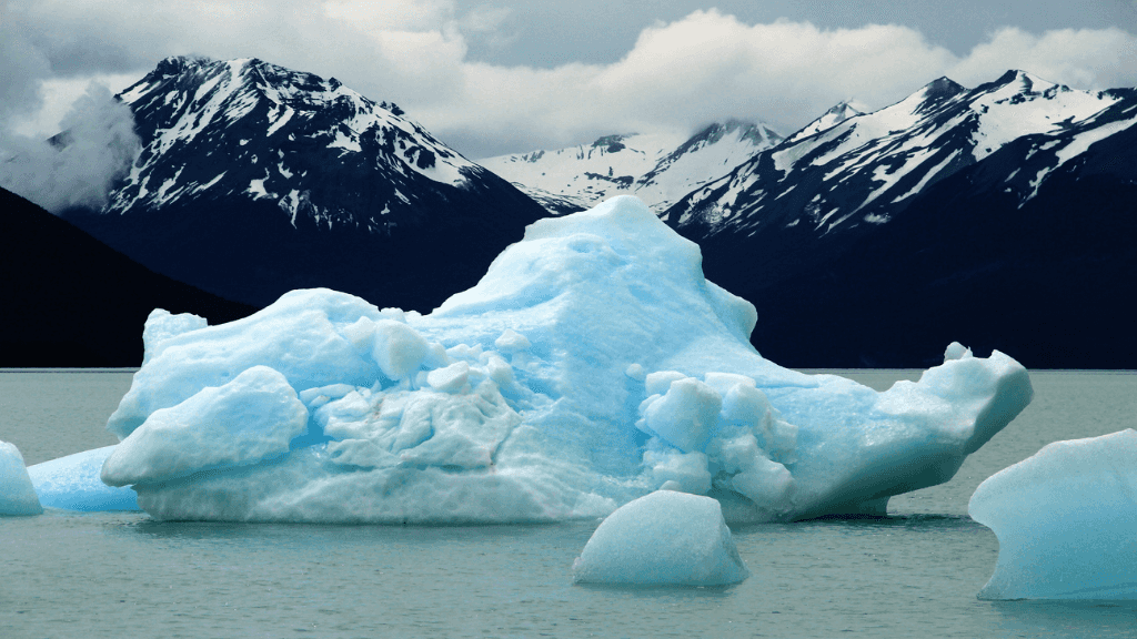 Floating icebergs in turquoise lake with snowy mountains in Patagonia, seen during the 9-day Blue Heart Adventure hiking tour. Glacier country highlights.