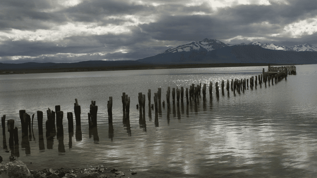 Weathered wooden pier stretching into Patagonian lake, part of the 9-day Blue Heart Adventure hiking tour. Serene stop on the Turquoise Lakes Circuit.
