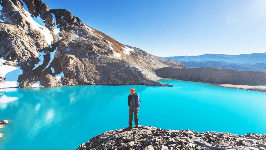 Hiker overlooking turquoise alpine lake in Torres del Paine during Patagonia Hiking Tours - Blue Heart Adventure | 9 Days. Ideal for nature lovers and trekking.