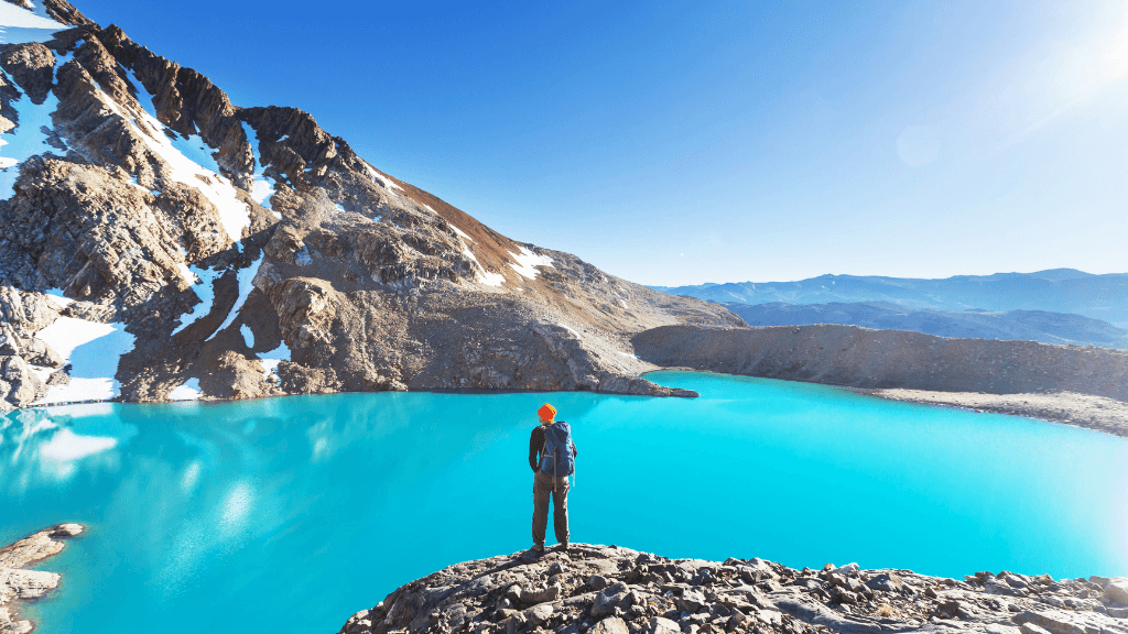Hiker overlooking turquoise alpine lake in Torres del Paine during Patagonia Hiking Tours - Blue Heart Adventure | 9 Days. Ideal for nature lovers and trekking.