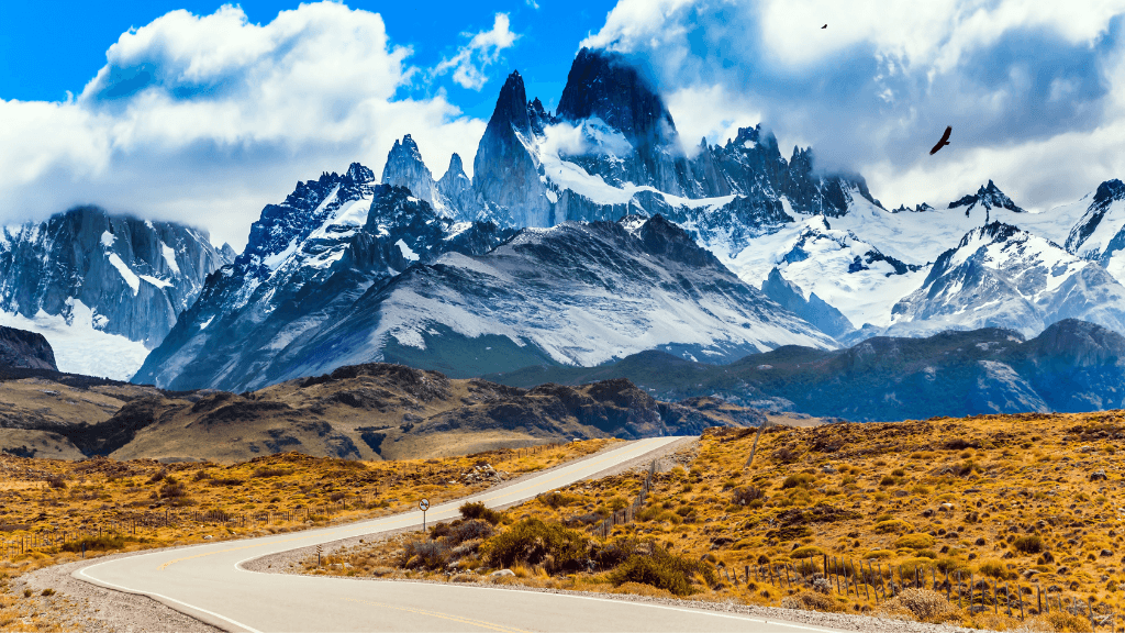 Winding road leading to snow-capped peaks in Patagonia, part of the 9-day Blue Heart Adventure hiking tour through Torres del Paine and Argentina.